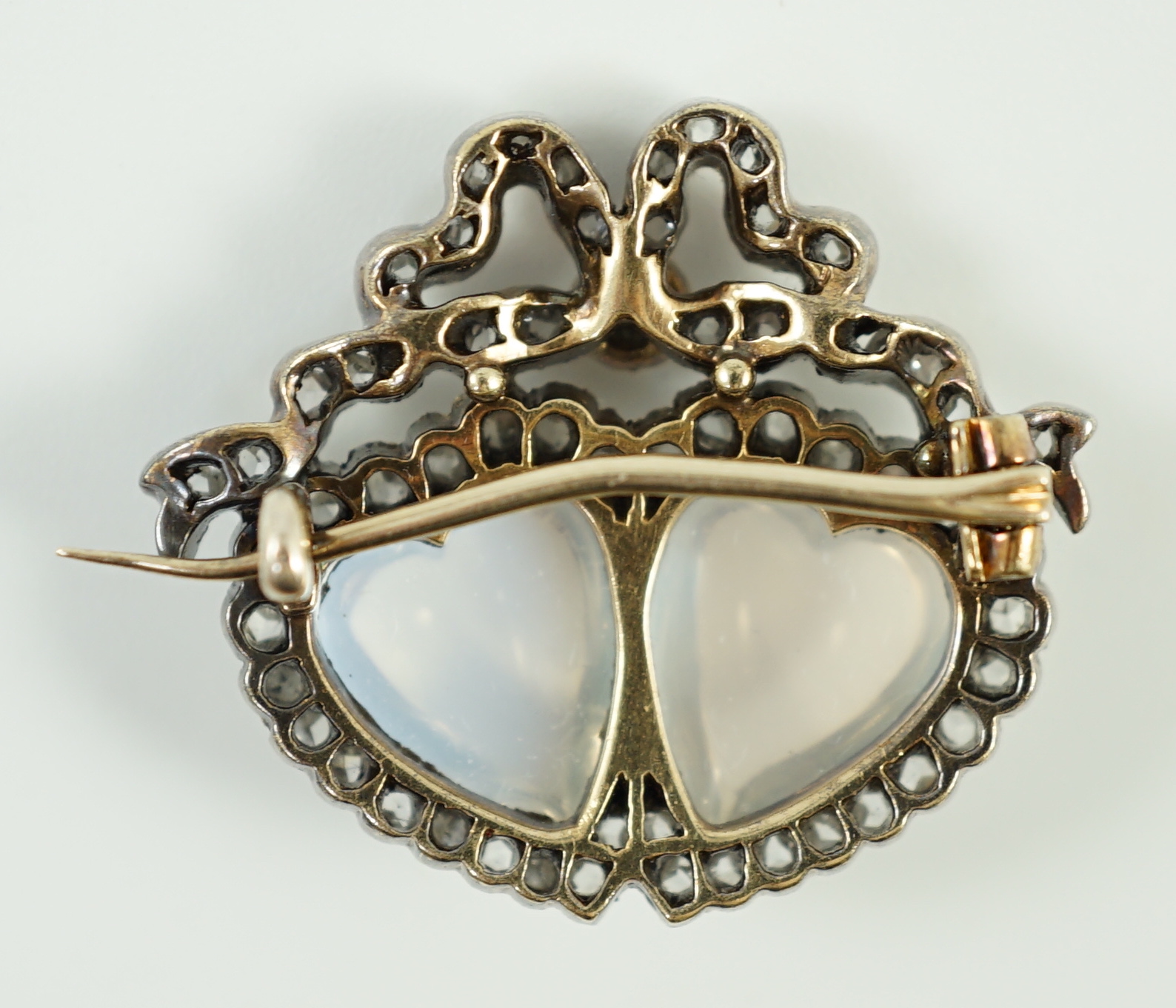 An Edwardian gold and silver, moonstone and diamond cluster set twin hearts brooch